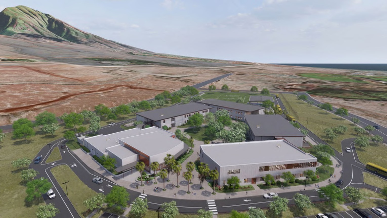 Aerial view of the planned campus on the Kuʻia site, with classroom and communal buildings arranged around courtyards and a sports field, the slopes of the West Maui mountains behind and the ocean beyond.